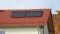 The picture shows a red house roof on which a solar thermal collector is mounted.